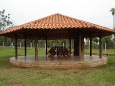 a gazebo sitting on top of a lush green field next to a park filled with palm trees