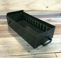 an empty black plastic tool box sitting on top of a wooden table