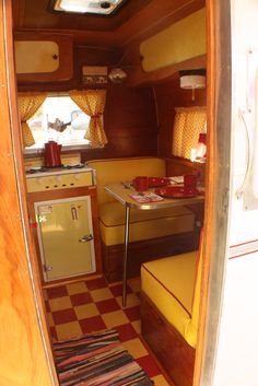 the inside of a camper with yellow and red decor, including a kitchen area