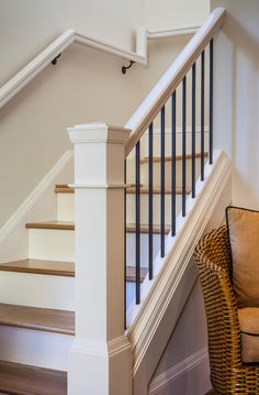 a wicker chair sitting next to a stair case in a room with white walls