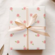 a gift wrapped in white paper with pink roses on it