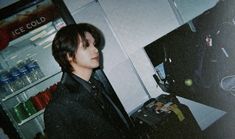 a young man standing in front of a refrigerator