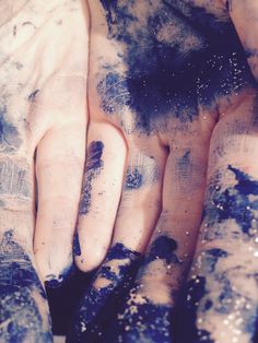 two hands are covered in blue and white paint with black spots on the top one hand