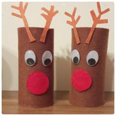 two toilet paper roll reindeers sitting on top of a wooden table