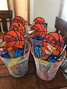 several baskets filled with snacks and basketballs on top of a wooden table in front of a window