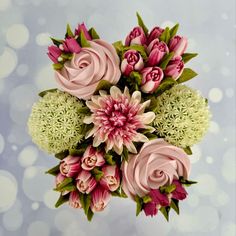 a bouquet of pink and white flowers with green leaves on a blue background in the air