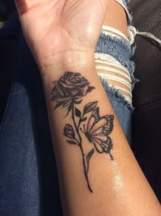 a woman's wrist with a rose and butterfly tattoo on her left arm,