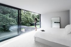 a woman is standing in the middle of a bedroom looking out onto the yard and trees