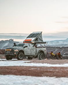 two men sitting in the back of a pick up truck with a solar panel on top