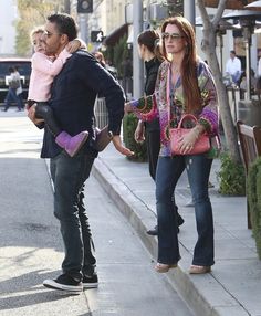 a man and woman walking down the street with a baby in her arms while holding hands