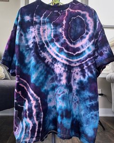 a purple and blue tie - dyed t - shirt hanging on a clothes hanger