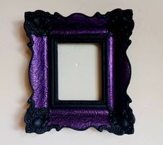 a purple and black frame hanging on the wall