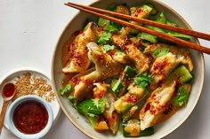 a white plate topped with chicken and veggies next to two chopsticks