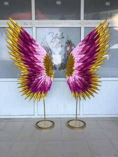 two pink and yellow wings are on display in front of a storefront with large windows