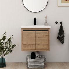 a bathroom with a sink, mirror and towel rack in it's corner next to a potted plant