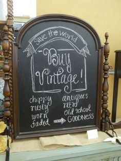 a chalkboard sign with writing on it in front of a store display case that says buy vintage