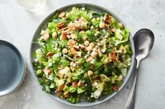 a salad with lettuce and nuts in a bowl next to a glass of water