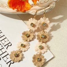 a pair of earrings with flowers hanging from them on a table next to a flower vase