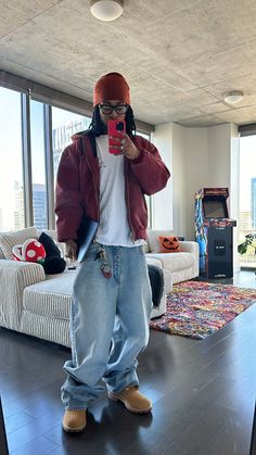 a person taking a selfie in a living room with a couch and large windows