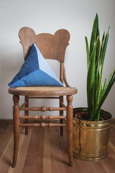 a wooden chair sitting next to a potted plant on top of a hard wood floor