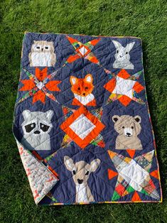 an animal themed quilt is laying on the grass