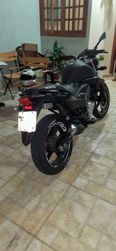 a black motorcycle parked on top of a tile floor next to a table and chairs