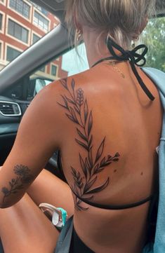 a woman with tattoos on her back sitting in a car