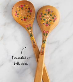 two wooden spoons with painted designs on them sitting next to each other, labeled decorated on both sides