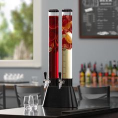 two red candles sitting on top of a black table next to wine glasses and bottles