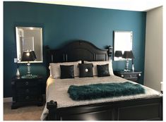 a bedroom with blue walls, black furniture and green fur rugs on the bed