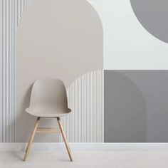 a white chair sitting in front of a wall with grey and white designs on it