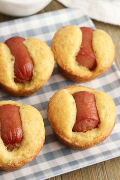 four hotdogs with ketchup in the middle on a checkered plate