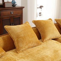 a bed with yellow linens in front of a window and wooden dresser next to it