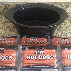 some hot dogs are sitting in front of a black pot on the counter next to them