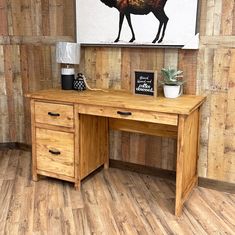 a wooden desk with two drawers in front of a painting on the wall behind it