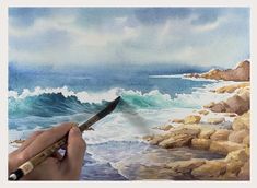 someone is painting waves on the rocks by the ocean with a brush and watercolor