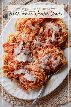 a white plate topped with pasta covered in sauce and parmesan cheese next to a fork