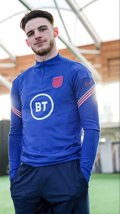 a man standing on top of a soccer field wearing a blue shirt and black shorts