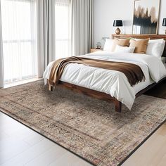 a large bed sitting on top of a wooden floor next to a window covered in curtains