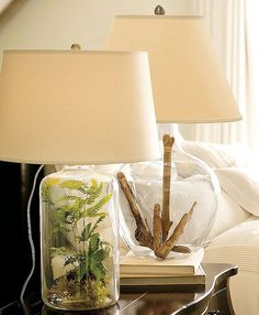 two lamps sitting on top of a table next to a lamp with plants in it