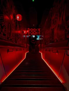 an escalator with red lights going down it in a dark room that has graffiti on the walls