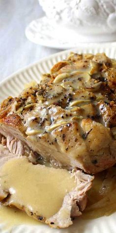 a white plate topped with meat covered in gravy and sauce on top of a table