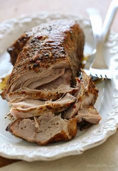 a white plate topped with sliced meat on top of a table