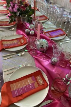 the table is set with silverware and pink napkins for an elegant dinner party