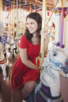 a woman in a red dress on a merry go round