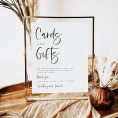 a card and gift sign sitting on top of a wooden table next to dried plants