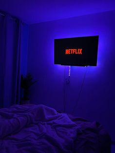 a neon sign that reads netflix on the wall above a bed in a dark room