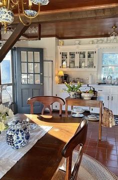 a dining room table and chairs in front of a kitchen with an open door leading to the outside