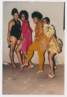 four women posing in front of a wall with their feet on one another's butts