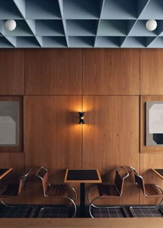 an empty table and chairs in a room with wood paneling on the walls,